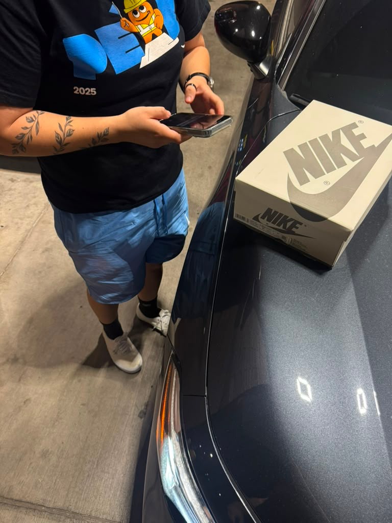 Customer checking sneaker order on car hood after delivery