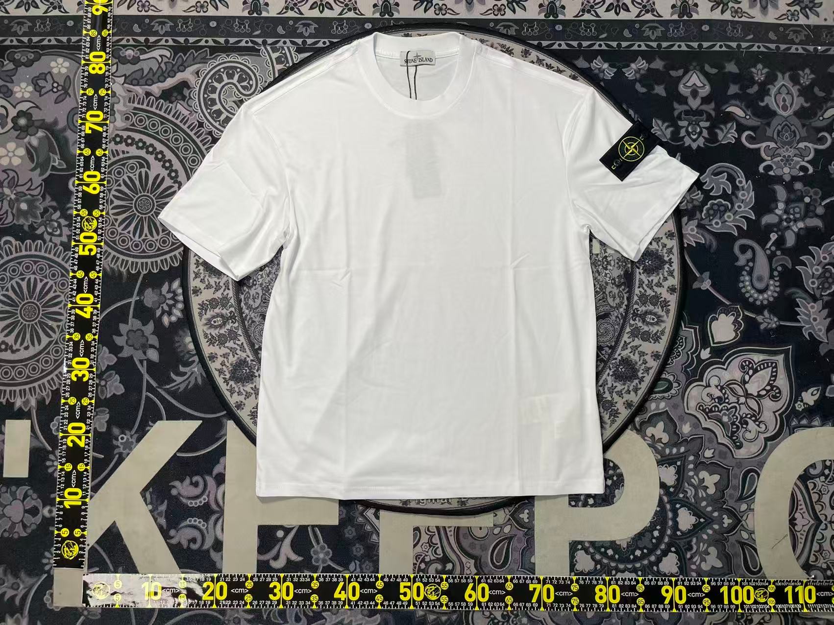 Stone Island White Tee — compass arm badge close-up